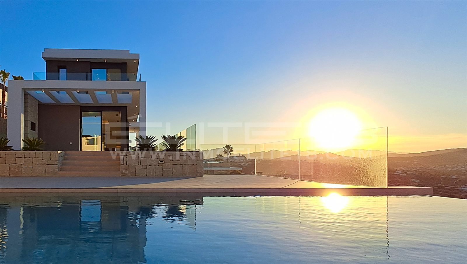 Puesta de sol reflejada en la piscina infinita de Villa Elysia